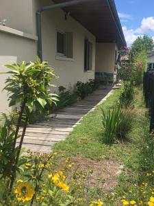 ein Haus mit einem Holzsteg neben einem Garten in der Unterkunft Charmant séjour à Andernos in Andernos-les-Bains