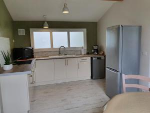 a kitchen with white cabinets and a stainless steel refrigerator at Charmant séjour à Andernos in Andernos-les-Bains