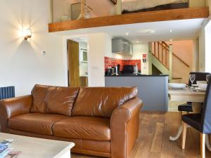 a living room with a leather couch and a kitchen at Swallow Barn in Hargrave