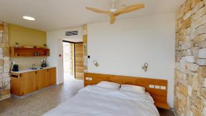 1 dormitorio con cama y pared de piedra en Genesis Land Desert hospitality, en Kfar Adumim