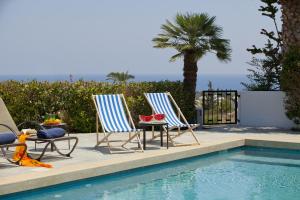 two chairs and a table next to a swimming pool at Ayios Elias Pearl in Protaras