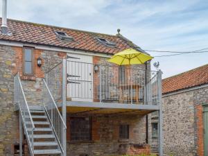 a house with a balcony with a yellow umbrella at The Chaff House in Wookey