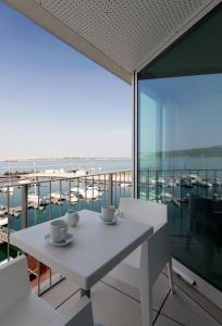 - une table et des chaises blanches avec vue sur l'océan dans l'établissement Troia Residence by The Editory - Apartamentos Marina, à Tróia