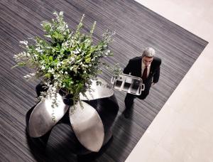 a man in a suit carrying a briefcase next to plants at Divani Apollon Suites in Athens