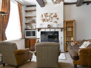 a living room with a couch and chairs and a tv at Primrose Cottage in Bowness-on-Windermere