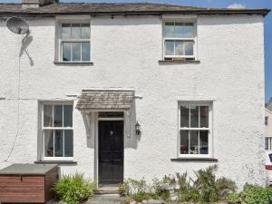 a white brick house with a door and windows at Primrose Cottage in Bowness-on-Windermere