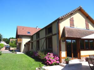 ein Haus mit großen Fenstern und einem Hof mit rosa Blumen in der Unterkunft Le Chemin d'Ulphe in Boves