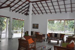 a living room with chairs and tables and windows at Aarya hotel in Pinnawala