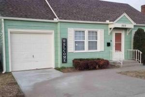 a green house with a white garage at BLUE FLAMINGO'S CHARMING HOME-Heart of Tulsa2- Cherry St-Expo-11th in Tulsa