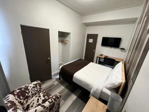 a small bedroom with a bed and a chair at Commercial Hotel in Edmonton