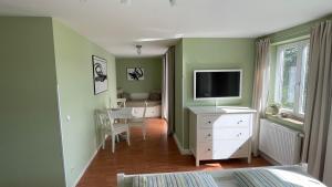 sypialnia z zielonymi ścianami i telewizorem na komodzie w obiekcie Waldgasthaus Balsamine w mieście Weimar