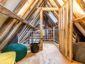 an attic room with wooden ceilings and green ottomans at Old Shires Barn in Norton