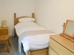 a bedroom with two beds and a dresser with a mirror at Thistle Cottage in Glanton