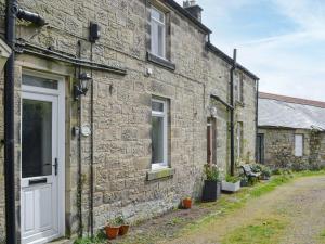 a brick house with a white door and a street at Thistle Cottage in Glanton