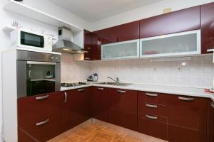 a kitchen with brown cabinets and a microwave at Apartments with a parking space Gradac, Makarska - 14708 in Gradac