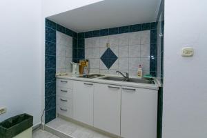 a small kitchen with a sink and blue tiles at Apartments with a parking space Gradac, Makarska - 14708 in Gradac