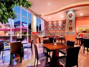 a restaurant with tables and chairs and windows at Ibis Bali Kuta in Kuta