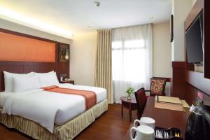 a hotel room with a large bed and a desk at Best Western Plus Makassar Beach in Makassar