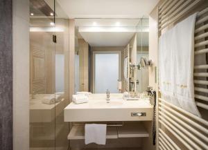a white bathroom with a sink and a shower at elaya hotel vienna city center in Vienna