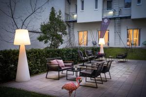 ein Flamingo steht auf einer Terrasse mit Stühlen und Tischen in der Unterkunft elaya hotel vienna city west in Wien