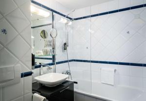 un bagno bianco con lavandino e vasca di Arthotel ANA Gala a Vienna