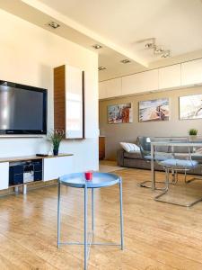 a living room with a table and a tv at Sailor Apartments - Neptun Park by OneApartments in Gdańsk