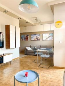 a living room with a table and a couch at Sailor Apartments - Neptun Park by OneApartments in Gdańsk