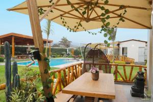 a patio with a table and an umbrella and a pool at Kuyayky Lodge in Lima