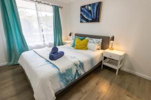 淺灘灣的住宿－Bay Dream Believer, Ample Boat Parking, Pet Friendly 4 br Holiday House Shoal Bay，一间卧室配有蓝色和黄色枕头的床