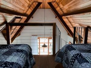 two beds in a room with a wooden ceiling at Chale Vale Encantado in São Bento do Sapucaí