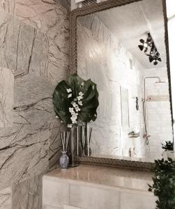 a bathroom with a mirror and a vase of flowers at Cozy Studio in Palanga City Center in Palanga