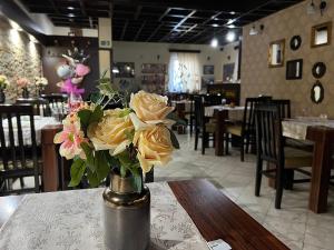 um vaso de rosas amarelas numa mesa num restaurante em Garni Hotel City em Kruševac