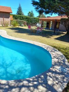 a blue swimming pool with a table in a yard at Cabañas De Cara al Sol in Villa Giardino