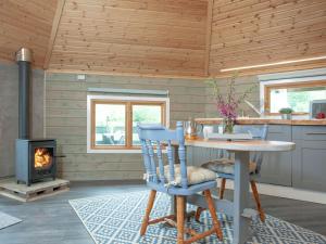 cocina con mesa, sillas y chimenea en Mallard Roundhouse - Uk33891 en Cullompton