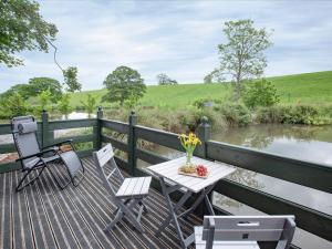 a table and chairs on a deck next to a river at Mallard Roundhouse - Uk33891 in Cullompton
