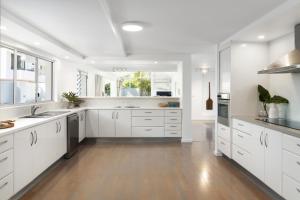 a large kitchen with white cabinets and a hardwood floor at Villa Bianco, 5 Key Court, Noosa Heads in Noosa Heads