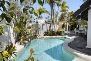 een zwembad in een tuin met bomen en een hek bij Villa Bianco, 5 Key Court, Noosa Heads in Noosa Heads