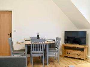 a dining room with a table with chairs and a tv at The New Inn Barn-uk31813 in Marnhull