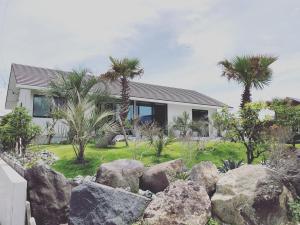 una casa con palmeras y rocas delante de ella en Villa Mariso “貸別荘マリソ“, en Noma