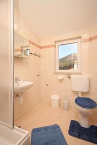 uma casa de banho com um WC, um lavatório e uma janela em Apartments with a parking space Seget Vranjica, Trogir - 8507 em Seget Vranjica