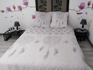 a bed with a white comforter with flowers on it at Maison rénovée pour 14 pers avec piscine chauffée, jardin, baby-foot, proche Puy du Fou et La Rochelle - FR-1-426-362 in LʼHermenault +27 photos