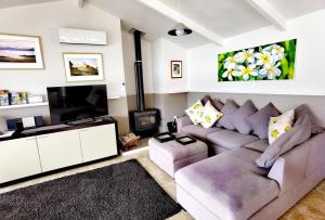 a living room with a couch and a tv at Water's Edge Holiday Home in Opua