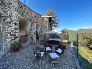 un patio con sillas, una mesa y una sombrilla en Flat with heated hot tub and shared pool, en Casola in Lunigiana