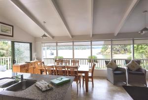 a kitchen and dining room with a table and chairs at Water's Edge Holiday Home in Opua