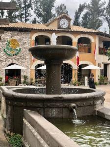 einen Brunnen vor einem Gebäude mit einer Uhr in der Unterkunft Increíble Loft Completo en Val'Quirico in Santeagueda