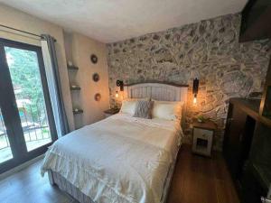 a bedroom with a large bed and a stone wall at Increíble Loft Completo en Val'Quirico in Santeagueda