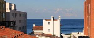 a white building with the ocean in the background at TAS D VIAJE Suites - Hostel Boutique in Punta del Este