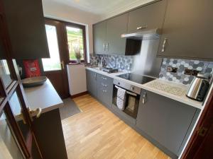 a kitchen with gray cabinets and a stove top oven at Highbury House in Camborne