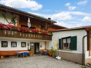 Cette maison dispose d'un balcon avec une table et des chaises. dans l'établissement Vintage Holiday Home in Vorarlberg near Ski Area, à Schwarzenberg im Bregenzerwald
