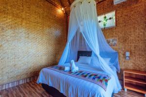 a bedroom with a bed with a mosquito net at Atuh Forest Cottage in Nusa Penida
